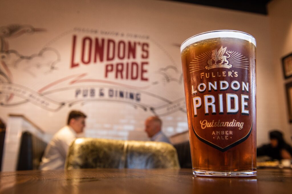 London Price pint on a table, behind a London Pride pub and dining sign 